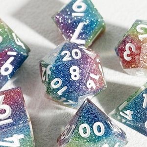 Könnte beinhalten: Sieben mehrfarbige, polyedrische Würfel mit Glitzer. Die Würfel haben verschiedene Formen und weiße Zahlen. Die Farben verlaufen von Rot über Blau bis Grün. Geeignet für Tabletop-Rollenspiele.