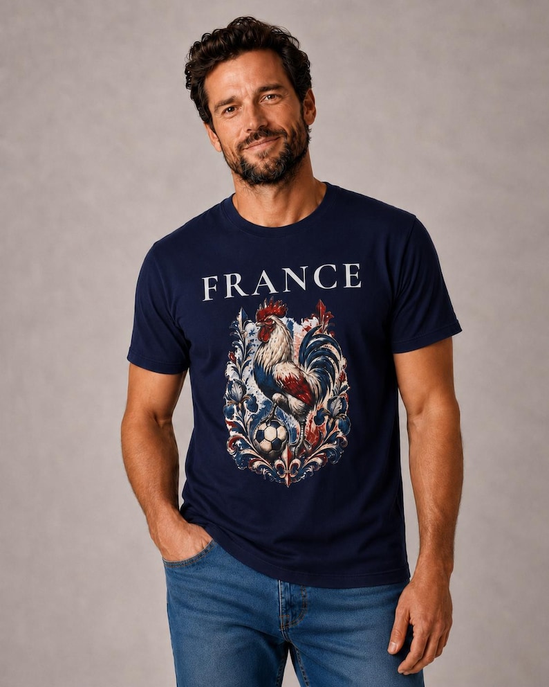 May include: Navy blue t-shirt with the word "FRANCE" in white block letters. The shirt features a detailed graphic of a rooster, a soccer ball, and ornate floral elements in red, white, and blue.