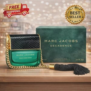 May include: A teal-colored Marc Jacobs Decadence perfume bottle with a black textured top and gold chain strap. The bottle is next to a matching green box with the brand name. The bottle has a black tassel and is 3.4 fl oz.