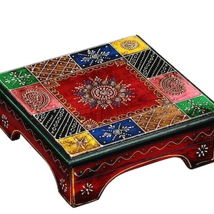 May include: A hand-painted wooden footstool with a vibrant, colourful design. The top features a red background with intricate floral and geometric patterns in various colours, including green, blue, yellow, and pink. The edges and legs are painted red with white accents.