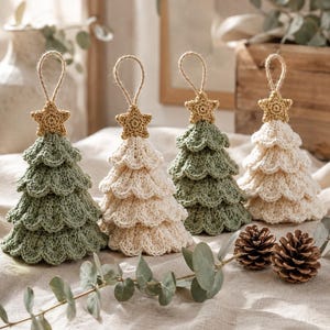 May include: Four crocheted Christmas tree ornaments in alternating sage green and cream colors. Each tree features three tiered layers of scalloped crochet stitches and is topped with a small, textured gold star and a jute twine hanging loop.