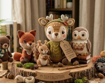 May include: A collection of six crocheted woodland animal figures including a bear, fox, squirrel, deer, owl, and hedgehog. The deer wears a green sweater and holds a tag labeled Forest Friend. A banner on the wooden base reads Cozy Collection.