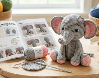 May include: A gray and pink crocheted elephant toy sitting next to an open instructional booklet titled Crochet Animal Patterns: Elephant. The scene includes a ball of cotton yarn, a metal crochet hook, scissors, and colorful stitch markers.
