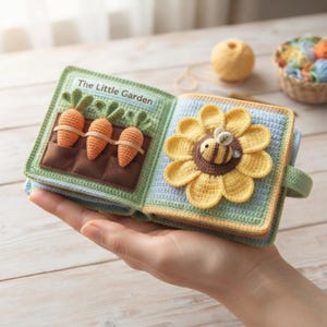 Può includere: Un libro sensoriale all'uncinetto fatto a mano intitolato The Little Garden. La pagina sinistra presenta tre carote arancioni con foglie verdi inserite in tasche di tessuto marrone. La pagina destra mostra un grande girasole giallo con una piccola ape a righe al centro.