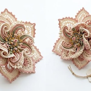 May include: A crocheted flower with intricate cream, dusty pink, and sage green threadwork. The flower features layered, lacy petals and a textured centre. A tag reads: The Wisteria Bloom, Unique Crochet Pattern by ELARA CROCHET, Etsy: ElaraCrochet.