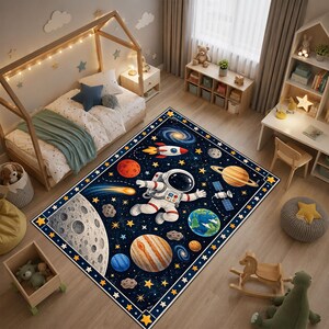 Könnte beinhalten: Ein rechteckiger Teppich mit einem dunkelblauen Weltraum-Design, das einen Astronauten in der Mitte, verschiedene Planeten wie die Erde und den Saturn, eine Rakete, einen Satelliten, einen großen Mond und verstreute gelbe Sterne zeigt.