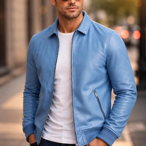 May include: A light blue leather jacket with a classic collar, a full-length silver front zipper, and two zippered side pockets. The jacket features ribbed cuffs and a hem, worn over a plain white t-shirt and dark blue denim jeans.