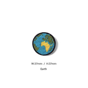 May include: A circular embroidered patch featuring a stylized depiction of the Earth with blue oceans, green landmasses, and a yellow continent. The patch has a black border and measures 37mm in width and 37mm in height, with the text Earth printed below.