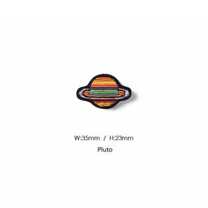 May include: An embroidered patch shaped like a planet with rings, featuring horizontal stripes in red, orange, yellow, green, blue, and purple. The patch has a black border and text below reading W:35mm / H:23mm and Pluto.