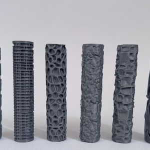 May include: Six cylindrical grey rollers arranged in a row, each featuring a distinct embossed surface pattern. The textures include geometric grids, organic honeycomb-like structures, irregular rocky formations, and angular lattice designs.