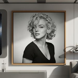 May include: A monochrome framed portrait of Marilyn Monroe. The image shows Monroe with blonde, curly hair and a black top with a V-neck. The portrait is displayed in a contemporary living room setting.