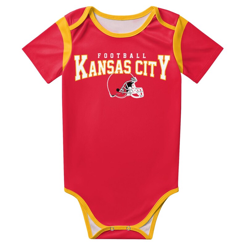 May include: A red short-sleeve baby bodysuit with yellow trim on the neckline, sleeves, and leg openings. The chest features the text "KANSAS CITY" in yellow block letters above a white football helmet graphic with the word "FOOTBALL" above it.