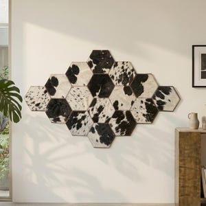 Pode incluir: Uma decoração de parede composta por vários azulejos hexagonais cobertos com pele de vaca preta e branca. Os azulejos estão unidos num grupo para formar uma grande forma geométrica de diamante na superfície da parede.