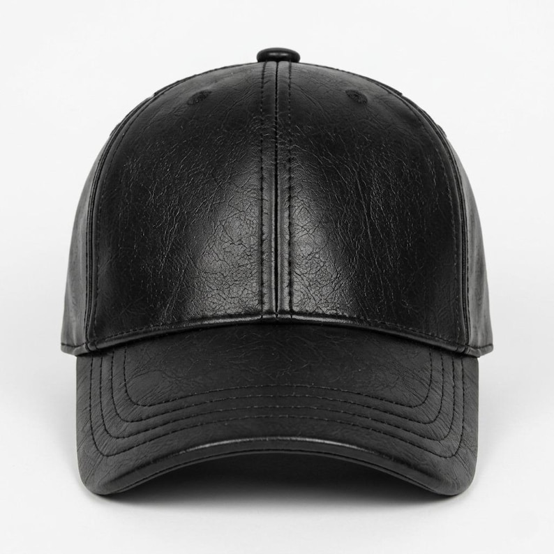 A black baseball cap with a textured, leather-like finish. The cap features a structured six-panel crown with a central button at the top and a curved brim with visible stitching detail along the edge of the visor and the crown panels.