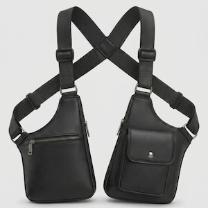May include: A black dual-pouch chest harness bag featuring adjustable elastic straps that cross at the back. The left pouch has a horizontal zippered pocket, while the right pouch features a flap pocket with a snap button closure and metal hardware.