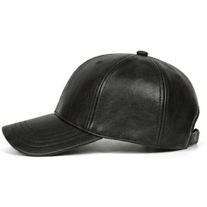 A black baseball cap with a textured, leather-effect finish. The cap features a structured six-panel crown, a curved brim with visible stitching, and an adjustable strap at the back. The material has a subtle, crinkled surface pattern.