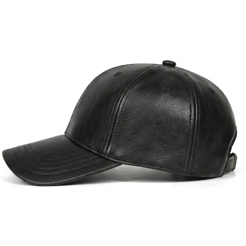 A black baseball cap with a textured, leather-effect finish. The cap features a structured six-panel crown, a curved brim with visible stitching, and an adjustable strap at the back. The material has a subtle, crinkled surface pattern.