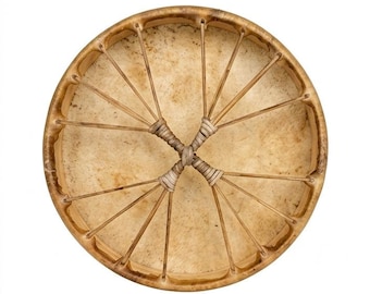 Peut inclure: Un tambour sur cadre circulaire avec une peau animale texturée de couleur beige clair. L'instrument présente un cerclage en bois et une série de fins lacets de couleur claire partant du bord vers le centre, où ils sont noués en forme de X.