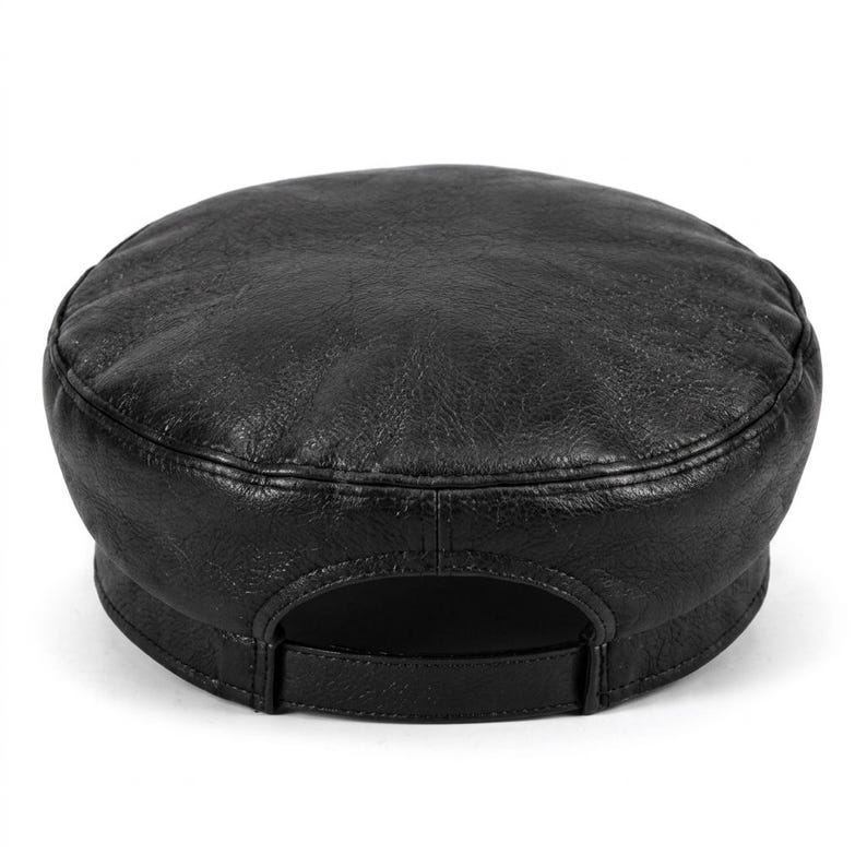 A black leather fiddler newsboy cap featuring a textured, slightly distressed surface, a rounded crown, and a structured brim. The back of the cap includes an adjustable strap with a matching black buckle for a secure and customisable fit.