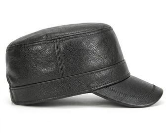 Peut inclure: Une casquette de style militaire noire avec une finition texturée semblable à du cuir. Le chapeau présente un dessus plat et structuré, une large bande entourant la base et une visière courte et incurvée avec des coutures visibles sur le bord.
