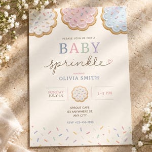 May include: A baby sprinkle invitation card featuring scalloped-edge cookie illustrations with pastel icing and sprinkles. Text reads: PLEASE JOIN US FOR A BABY sprinkle HONORING OLIVIA SMITH, SUNDAY JULY 15, 1-3 PM, SPROUT CAFE 123 ANYWHERE ST, ANY CITY, RSVP +123-456-7890.