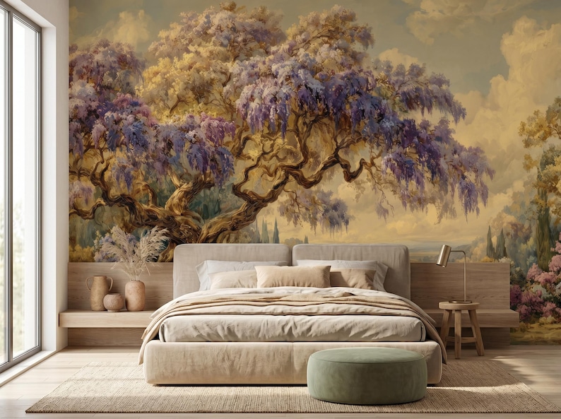 May include: A bedroom with a large mural of a tree with purple flowers and a beige bed. The mural is the focal point, with the tree's branches and flowers dominating the scene. The bed has a neutral color palette, with beige bedding and pillows. A small side table and ottoman complete the room.