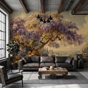 May include: A living room with a large mural of a tree with purple flowers. A black leather sofa and a wooden coffee table with books and a vase are in front of the mural. A black chair and a potted plant are also in the room.