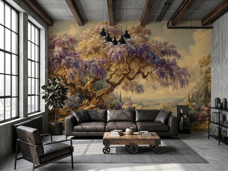 May include: A living room with a large mural of a tree with purple flowers. A black leather sofa and a wooden coffee table with books and a vase are in front of the mural. A black chair and a potted plant are also in the room.