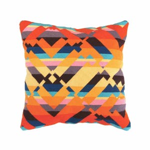 Puede incluir: Una almohada de tiro colorida con un patr&oacute;n geom&eacute;trico en tonos de naranja, amarillo, azul, rosa y morado. La almohada est&aacute; hecha de un tejido tejido y tiene una forma cuadrada.