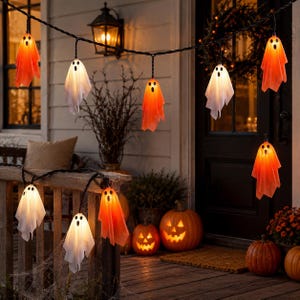 May include: A string of LED ghost lights featuring multiple white and orange fabric ghost figures with black eyes and mouths. The ghosts are illuminated from within, hanging from a black wire, creating a decorative lighting display.