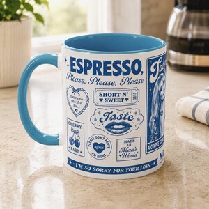 May include: A white ceramic mug with a bright blue interior and handle, featuring blue graphic prints including the text "ESPRESSO, Please, Please, Please", "SHORT N' SWEET", "Taste", "CHERRY BABY", "MADE IN Man's World", and "I'M SO SORRY FOR YOUR LOSS."