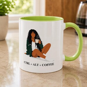 May include: A white ceramic mug with a lime green interior and handle. The front features an illustration of a person with long dark hair wearing a green jacket and white top, holding a mug. Below the illustration is the text CTRL + ALT + COFFEE.