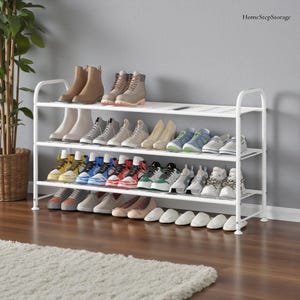 May include: A white metal shoe rack with three shelves, filled with various shoes, including boots, sneakers, and heels. The shoes are in different colors and styles. The rack is against a gray wall and a wooden floor.