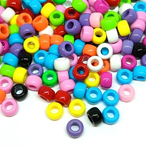 May include: A large collection of plastic pony beads in a variety of vibrant colors including red, orange, yellow, green, blue, purple, pink, white, and black. Each bead features a smooth, glossy finish and a central hole for threading purposes.