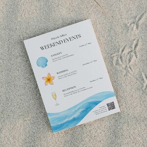 Pode incluir: Um itinerário de eventos de casamento branco na areia. Apresenta os nomes Priya & Aditya e as palavras "Weekend Events". Inclui ilustrações de uma concha, uma flor e uma taça de champanhe. A parte inferior tem um design de onda em aquarela azul.
