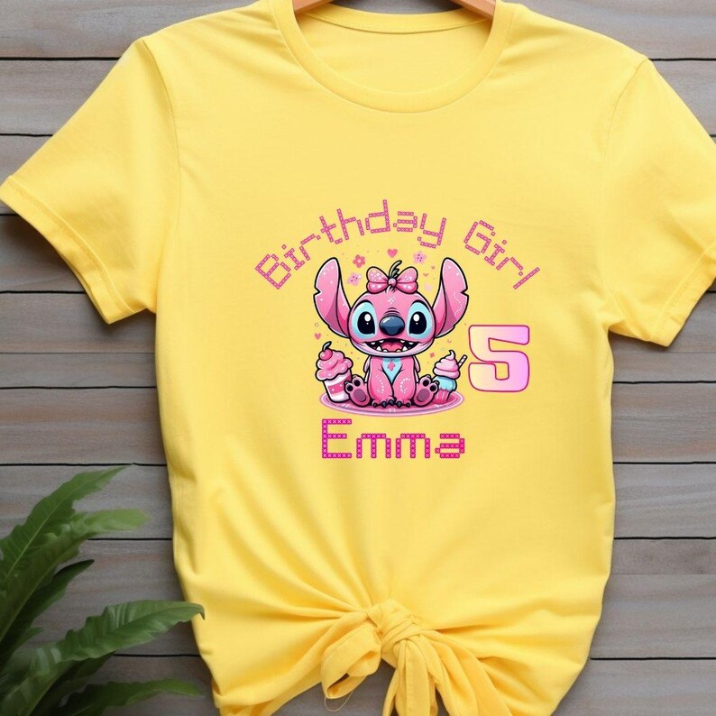 May include: Yellow t-shirt featuring a pink cartoon character with the text "Birthday Girl 5 Emma". The character is holding two cupcakes. The text and character are in pink and purple.