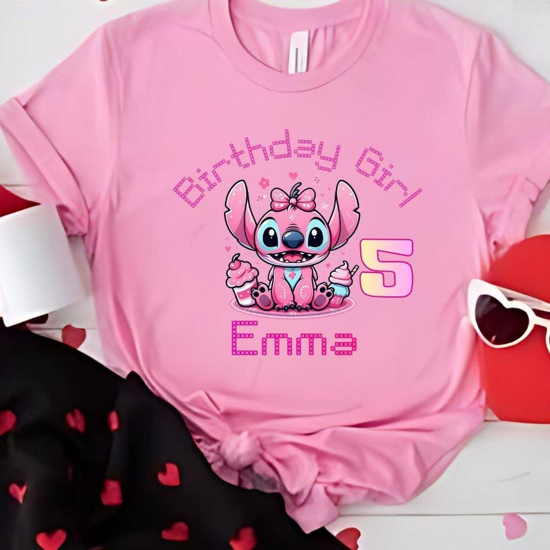 May include: Pink t-shirt featuring a cartoon character holding cupcakes, with the text "Birthday Girl", the number "5", and the name "Emma". The design is in shades of pink and purple.