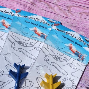 Puede incluir: Tres p&aacute;ginas para colorear con aviones, nubes y un sol. Cada p&aacute;gina tiene un mensaje de agradecimiento que dice "&iexcl;Gracias por volar!" y "Tu amigo, Snazzy".