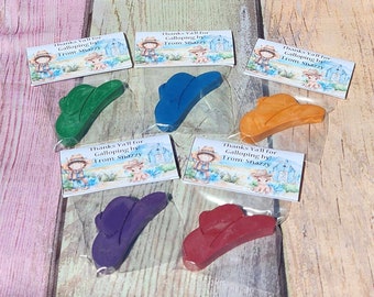 May include: Six individual bags of cowboy hat shaped crayons. Each bag has a thank you tag with a cartoon cowboy and the text "Thanks Y'all for Galloping by! From: Snazzy". The crayons are in the colors green, blue, orange, purple, and red.