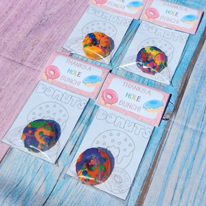 May include: Four clear plastic bags with colorful donut-shaped crayons and a printable coloring page that says "Thanks a Hole Bunch! Donuts".