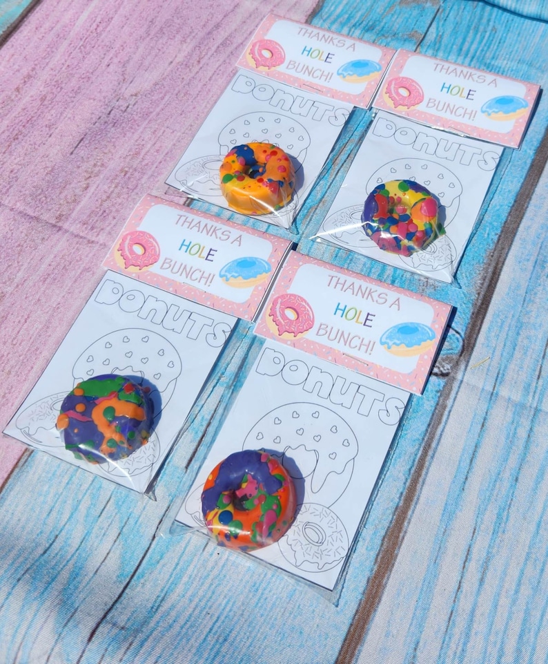 May include: Four clear plastic bags with colorful donut-shaped crayons and a printable coloring page that says "Thanks a Hole Bunch! Donuts".