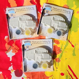 May include: Three school bus-shaped paint kits. Each kit includes a school bus-shaped ceramic figure, two paint colors, and a paintbrush. The cards read "Thank you for Rolling By!" and feature a school bus graphic.
