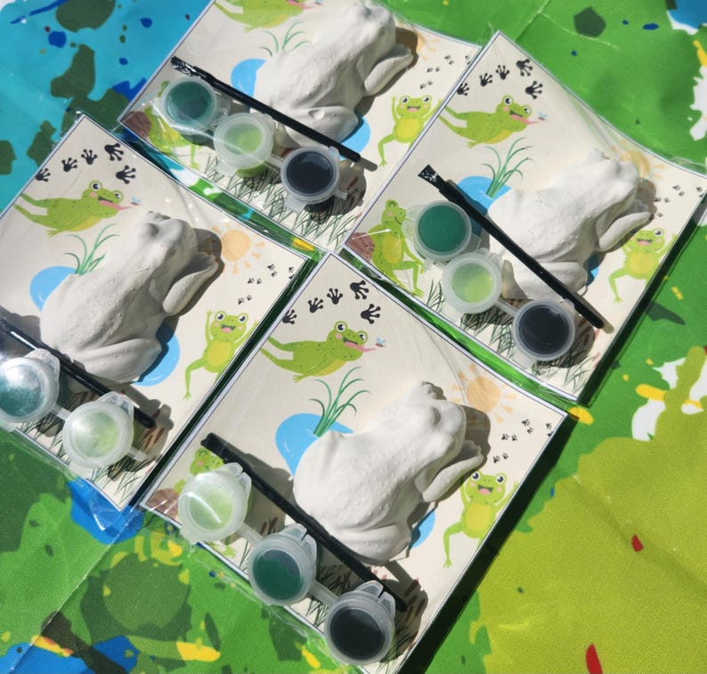May include: Four sets of frog-shaped ceramic figurines with paint and brushes for painting. Each set includes three paint pots, a brush, and a frog figurine.