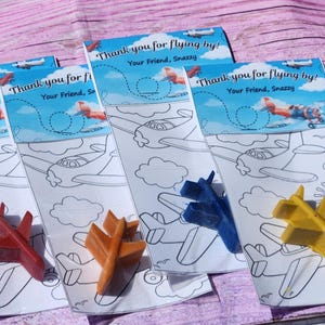 Puede incluir: Cuatro p&aacute;ginas para colorear con aviones y un cray&oacute;n de avi&oacute;n azul, amarillo, rojo y naranja. Las p&aacute;ginas para colorear tienen el texto "&iexcl;Gracias por volar! Tu amigo, Snazzy" en la parte superior.