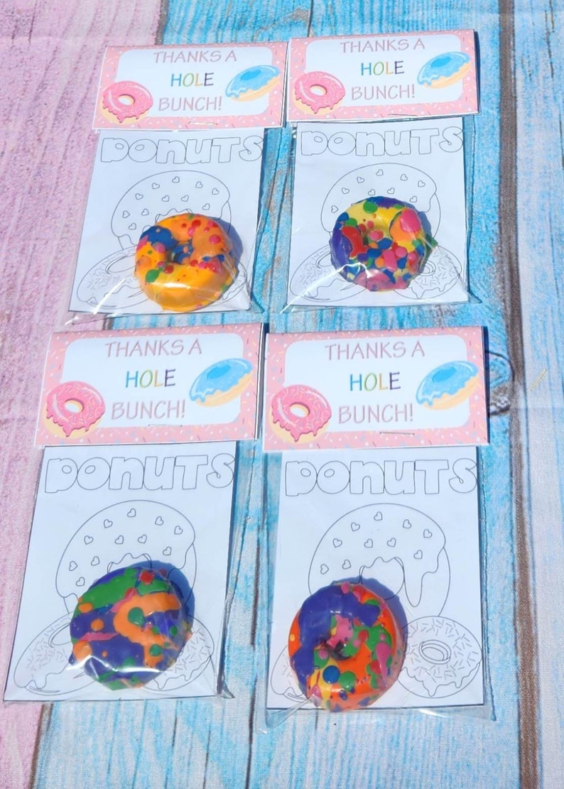 May include: Four clear plastic bags with colorful donut-shaped crayons inside. Each bag has a pink and white card with the text "Thanks a Hole Bunch!" and a donut illustration. The bags are labeled "Donuts".