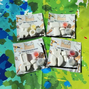 May include: Four white plastic tool-shaped party favours with paint pots and thank you tags. The tags say "Thank you for building with me!" and "From [Name]".
