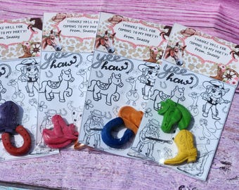 May include: Five colorful party favors with a western theme. Each favor includes a coloring page with a cowboy or cowgirl, a horse, and the words "Yee Haw". The favors also include a small, colorful, plastic toy shaped like a horseshoe, a boot, or a horse head.