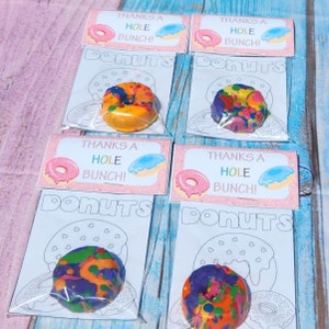 May include: Four favor bags with a donut-shaped coloring page and a small donut-shaped crayon. The bags have a pink background with the text "Thanks a Hole Bunch! Donuts".