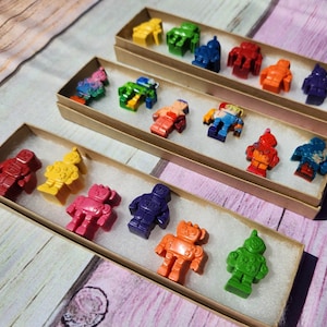 May include: A set of 10 colorful robot crayons in individual boxes. The crayons are arranged in a rainbow pattern, with each robot having a different color and design.
