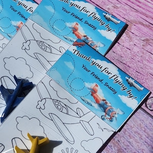 Puede incluir: Un conjunto de tres tarjetas de agradecimiento azules y blancas con un dise&ntilde;o de avi&oacute;n de dibujos animados. Las tarjetas dicen "&iexcl;Gracias por volar!" y "Tu amigo, Snazzy".
